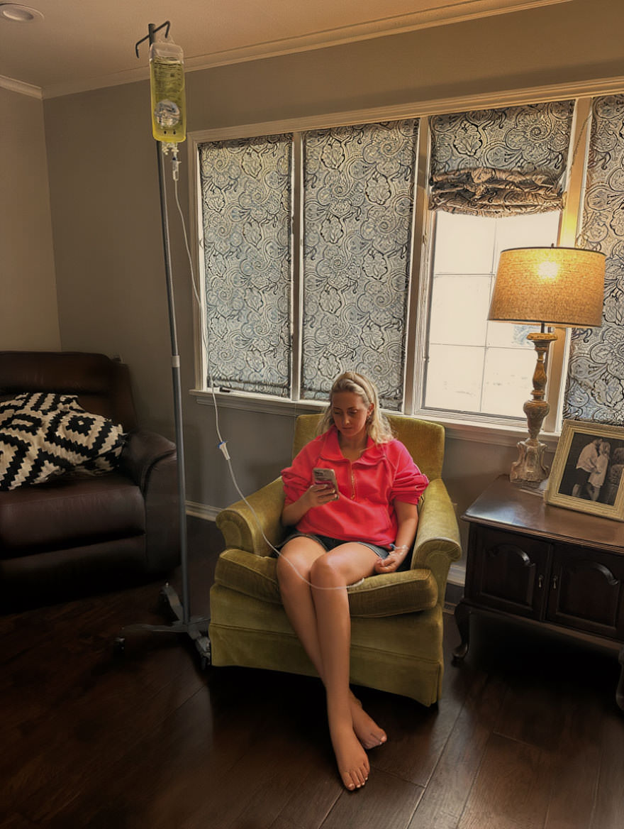 Woman at home on her phone while receiving IV therapy in Tulsa.